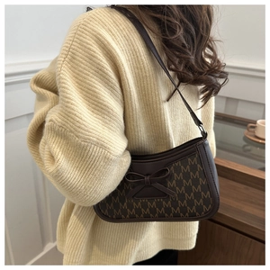 Detail of dark brown underarm bag featuring M-pattern monogram and leather bow knot