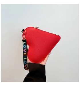 Détail de la pochette cœur rouge en cuir avec dragonne LOVE tissée et fermeture dorée