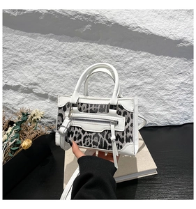 Detail of white leather leopard print mini handbag with dual cylindrical handles and zipper