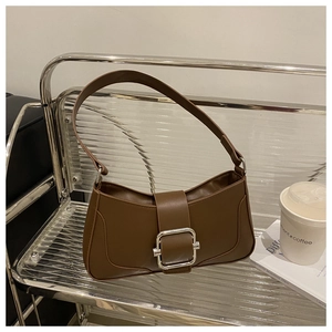 Detail of a dark brown leather underarm bag with a large silver buckle on a shelf