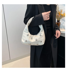 Detail of off-white crescent bag featuring silver metal studs and soft pleated leather texture