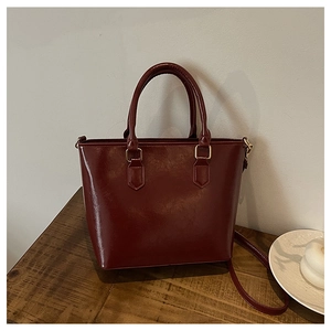 Détail du sac seau bordeaux en cuir PU avec garnitures dorées sur bois