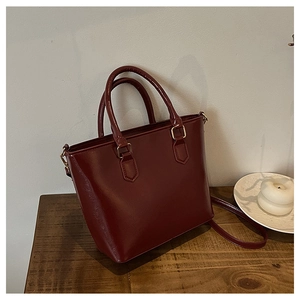 Détail du sac cabas bordeaux en cuir brillant avec accessoires dorés et sangle