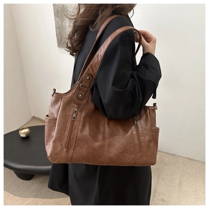 Detail of vintage brown leather tote bag with functional zippers and side pockets