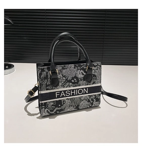 Detail of black and white patterned tote bag featuring a Fashion band and leather handles