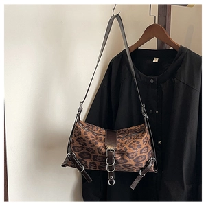 Dettaglio borsa a tracolla leopardata con anelli metallici e finiture in pelle marrone