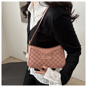 Detail of pink crescent bag with M-pattern print and golden bow buckle on model