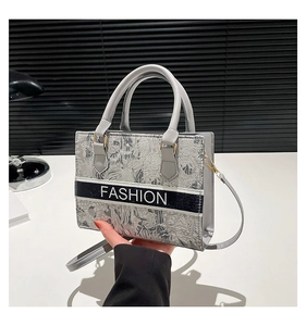 Detail of the gray jacquard fabric texture and Fashion logo on this small crossbody bag