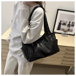 Close-up of black leather tote bag with functional zippers and detailed texture