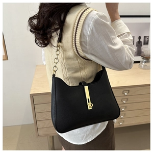 Détail du sac croissant en cuir noir avec chaîne dorée épaisse et fermoir métallique chic