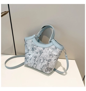 Detail of light blue leather stitching and jacquard fabric texture on the bucket bag