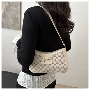 Detail of off-white crescent bag with M-pattern print and golden bow buckle decoration