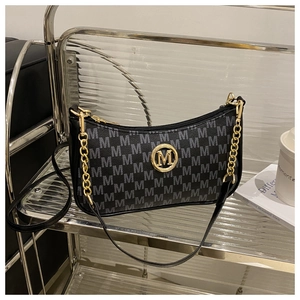 Détail du sac bandoulière noir avec monogramme M, logo doré et chaîne décorative