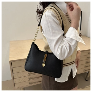 Détail du sac sous le bras en cuir noir grainé avec boucle dorée et bandoulière en chaîne