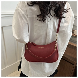 Detail of red crescent moon bag featuring litchi texture and gold chain strap