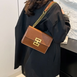 Brown glossy leather square shoulder bag with gold hardware and chain strap on a model