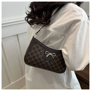Detail view of brown monogram crescent bag with golden bow buckle and leather strap