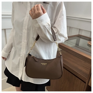 Detail of dark brown crescent bag with lychee texture and gold chain strap worn by model