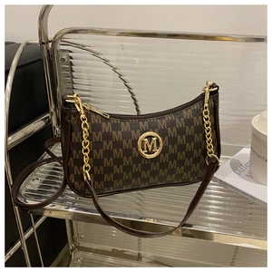 Détail du sac croissant avec monogramme M vintage et logo rond en métal doré brillant