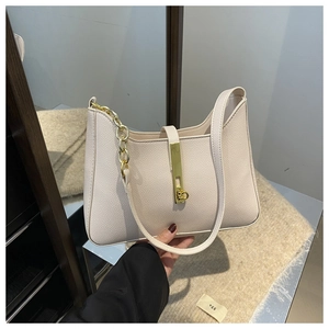 Détail du sac croissant beige avec chaîne dorée et fermoir métallique sur le cuir