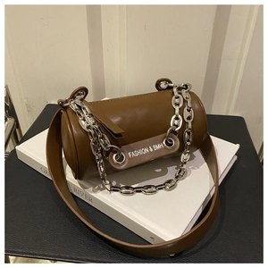 Detail view of brown cylinder crossbody bag with wide strap and silver metal chain