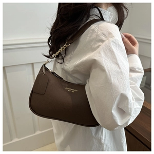 Detail of dark brown lychee leather crescent bag with gold chain and printed lettering