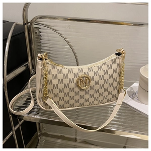 Détail du sac croissant crème avec motif monogramme gris et logo M en métal doré