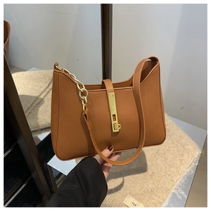 Détail du sac sous le bras en cuir grainé marron avec boucle dorée et bandoulière chaîne