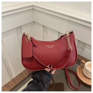 Close-up of red lychee pattern leather crescent bag with gold hardware and logo detail