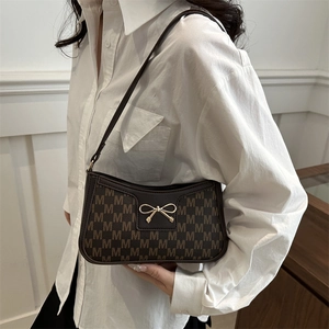 Dark brown crescent shoulder bag with M-letter print and golden bow detail on strap