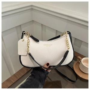 Detail of white litchi pattern crescent bag with black trim and gold chain strap