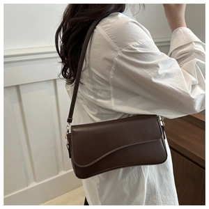 Detail of a dark brown leather underarm bag with unique irregular curved flap design