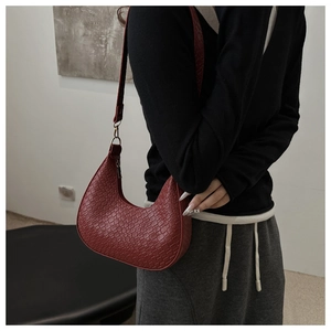 Detail view of burgundy crescent hobo bag with crocodile pattern and golden buckle