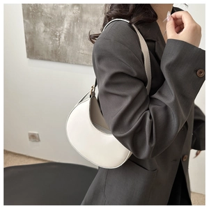 White minimalist hobo bag styled on woman shoulder with elegant crescent shape