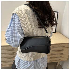 Minimalist black leather underarm bag with gold metal buckles shown on a model