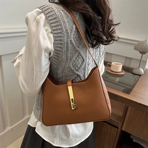 Sac hobo en cuir caramel avec fermoir doré porté par un mannequin à l'épaule