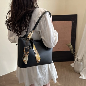 Black leather tote bag with white contrast stitching and floral scarf for daily commute