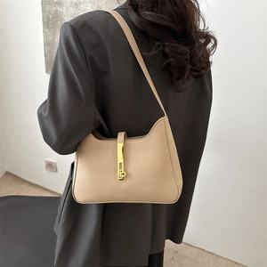 Sac hobo minimaliste en cuir beige avec fermoir en métal doré porté par un modèle