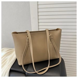 Detail of beige faux leather tote bag with contrast white stitching and long straps