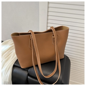 Detail of caramel faux leather tote bag showing white contrast stitching and slim straps