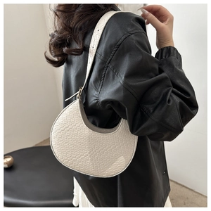 Detailed woven texture and crescent shape of the white shoulder bag shown on a model