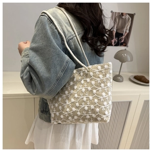 Vue détaillée du sac cabas beige avec broderies florales blanches et anses en corde