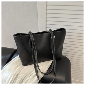 Detail of black tote bag featuring white contrast stitching and minimalist leather texture