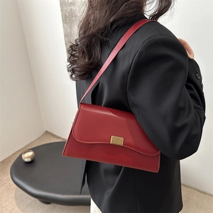 French style red leather underarm bag with gold buckle worn on black blazer