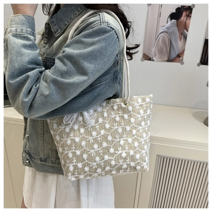 Détail du cabas tissé beige avec broderies florales blanches et poignées en corde