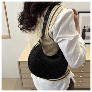 Detail of black crescent shoulder bag with crocodile pattern texture on a model