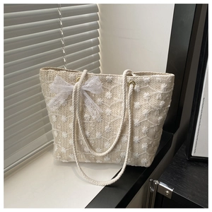 Détail du cabas tissé beige avec broderie de marguerites 3D et nœud en dentelle délicat