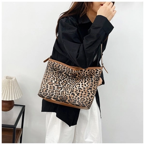 Dettaglio della borsa tote leopardata con finiture in pelle marrone indossata da modella
