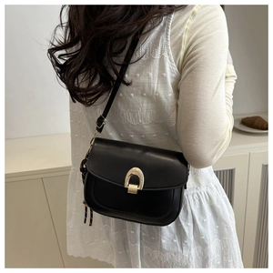 Detail of black crossbody bag with gold horseshoe buckle and printed silk scarf charm