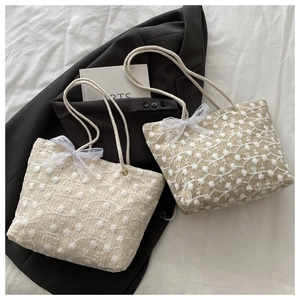 Détail de sacs fourre-tout en paille avec broderie marguerite et nœud en dentelle